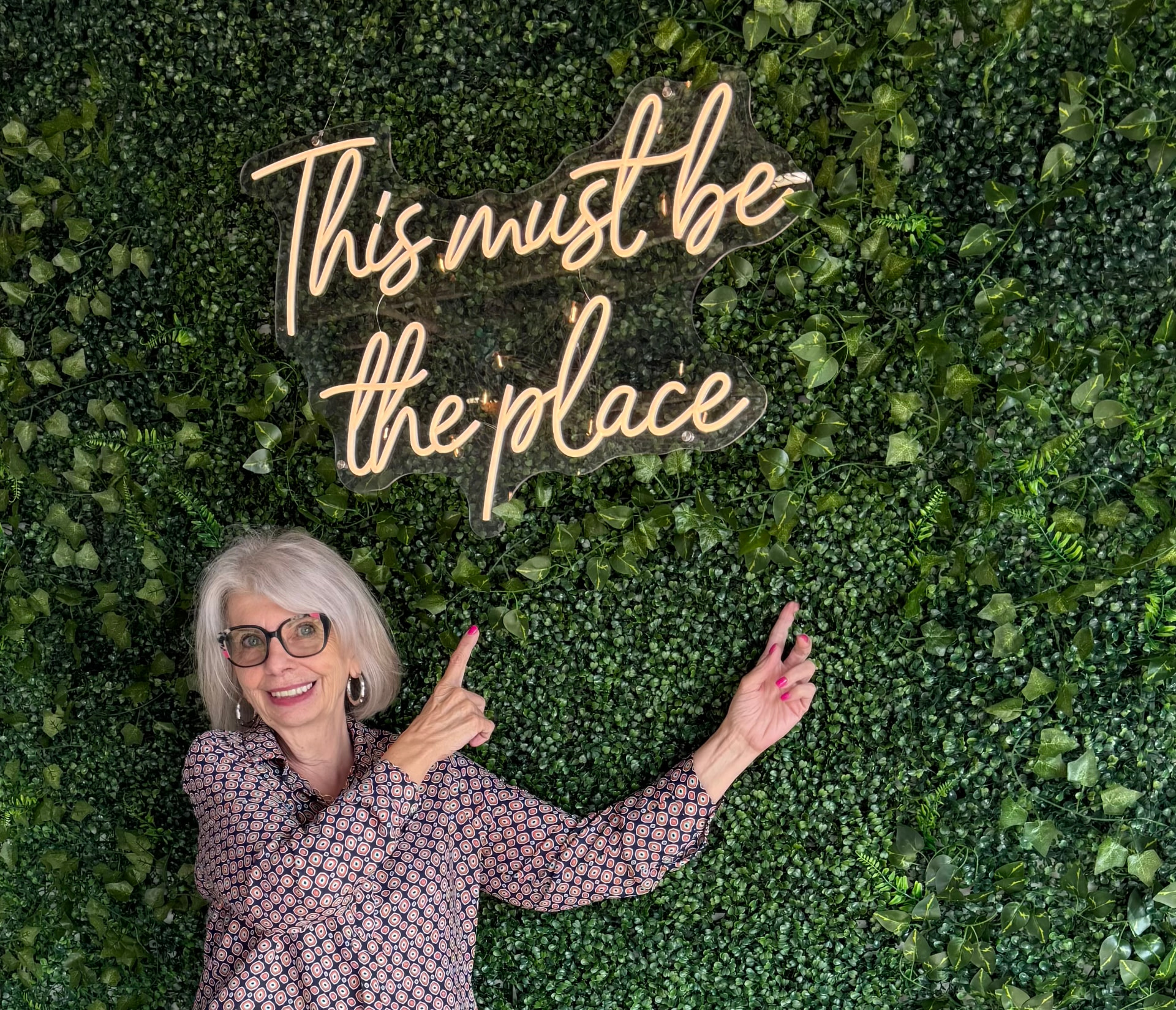 Ellen Timms pointing to a 'This must be the place' sign at a community space