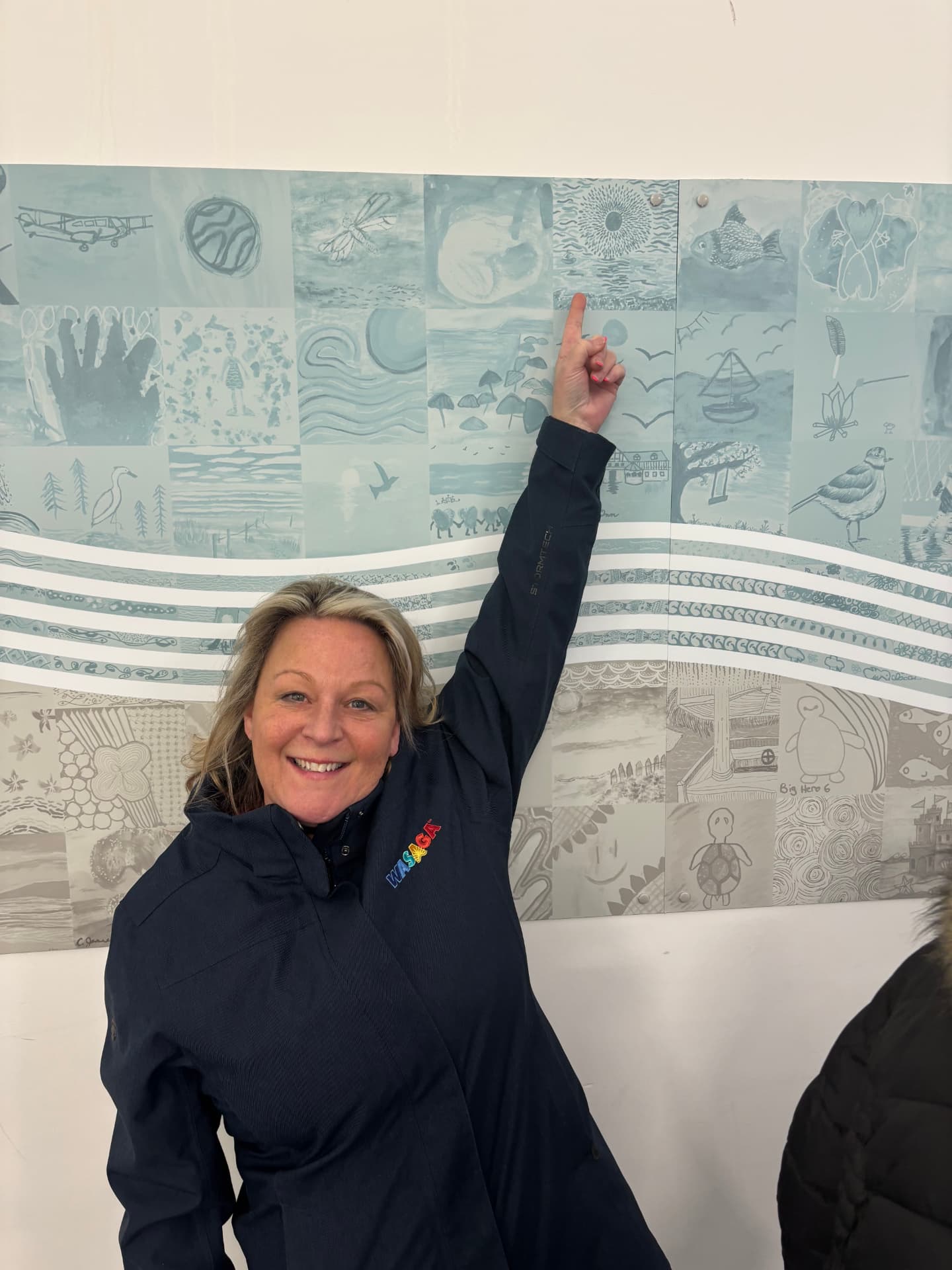 Tanya Snell pointing to a community mosaic mural